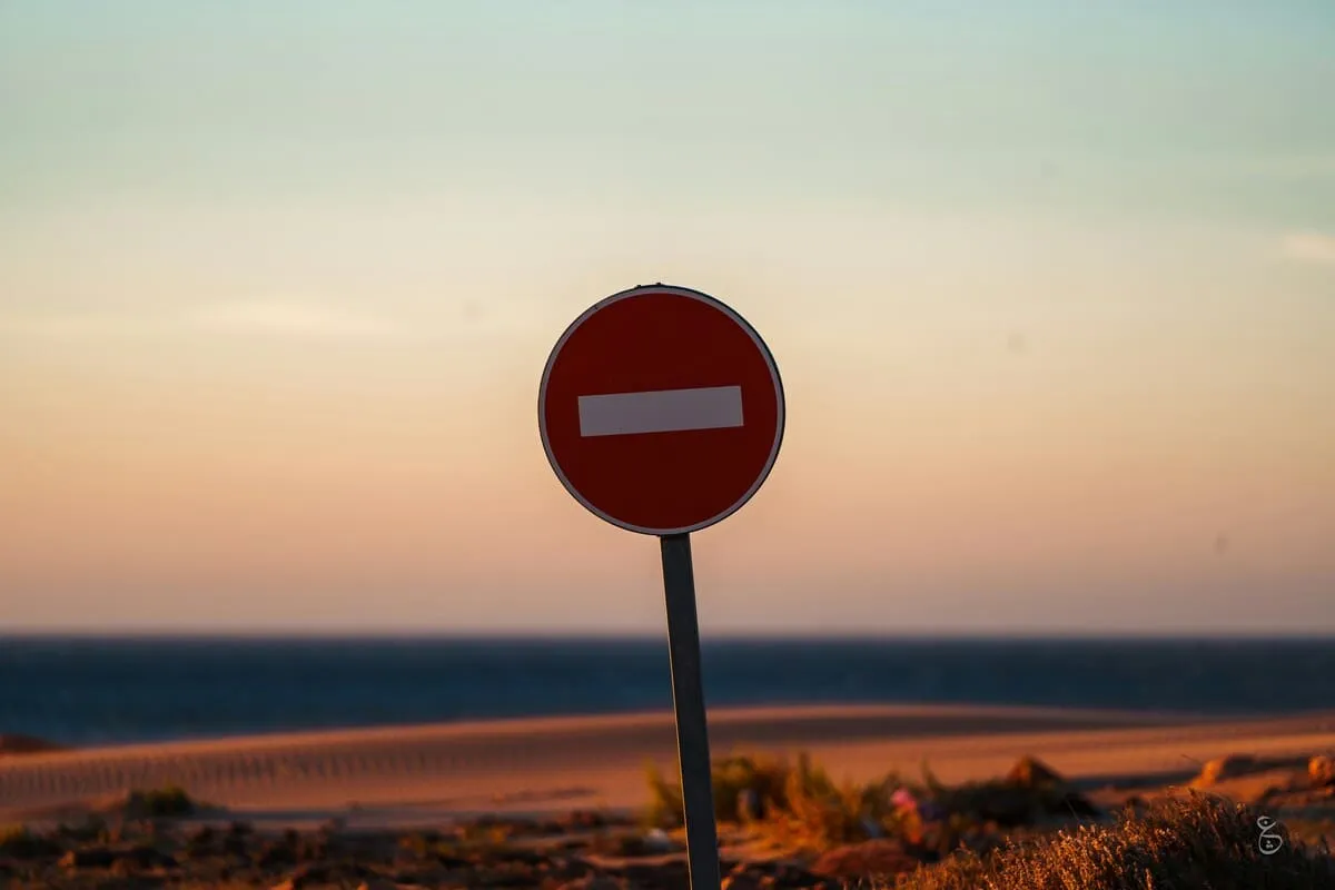 A red street sign sitting on the side of a road